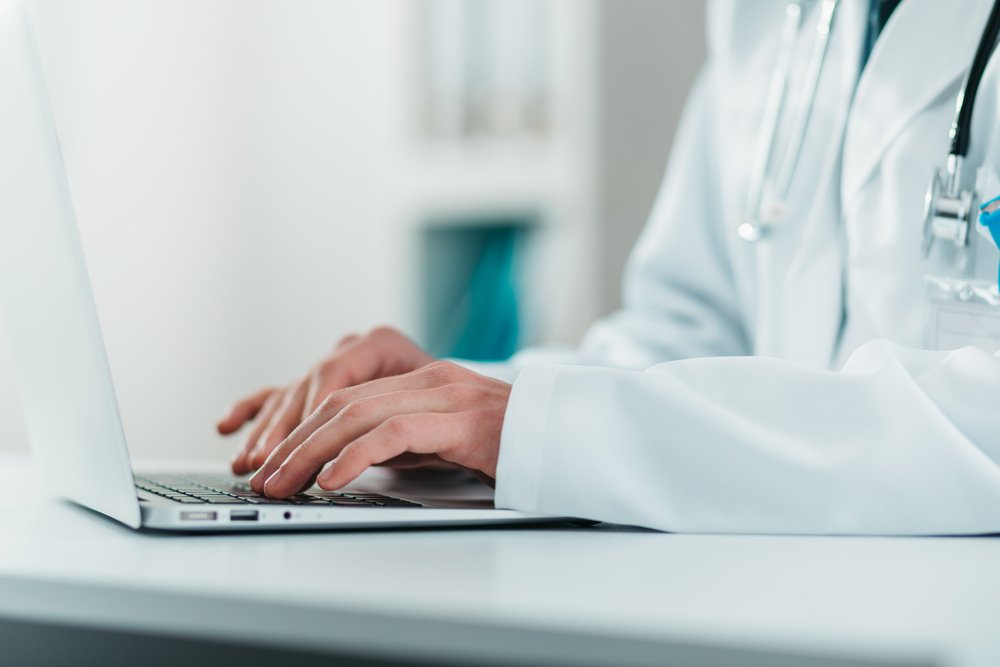 Detail of Young Doctor on the Job working on laptop. Volunteer at the hospital gains practical knowledge in treating disease